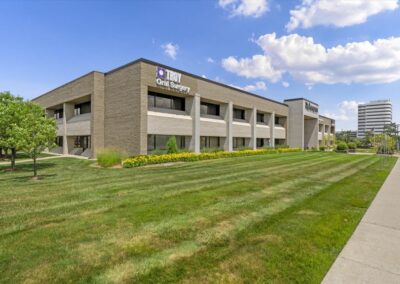 Two-story Class A office building on Big Beaver Road in Troy, Michigan, with Troy Oral Surgery signage on the upper facade, a lawn and office towers behind
