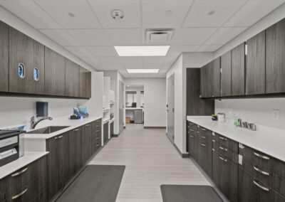 Modern sterilization room at Troy Oral Surgery in Troy, Michigan, with dark wood cabinets and white counters on both sides, a sink and a sterilizer